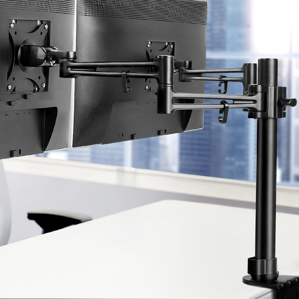 Monitor stand holding two computer monitors with a blurred office background