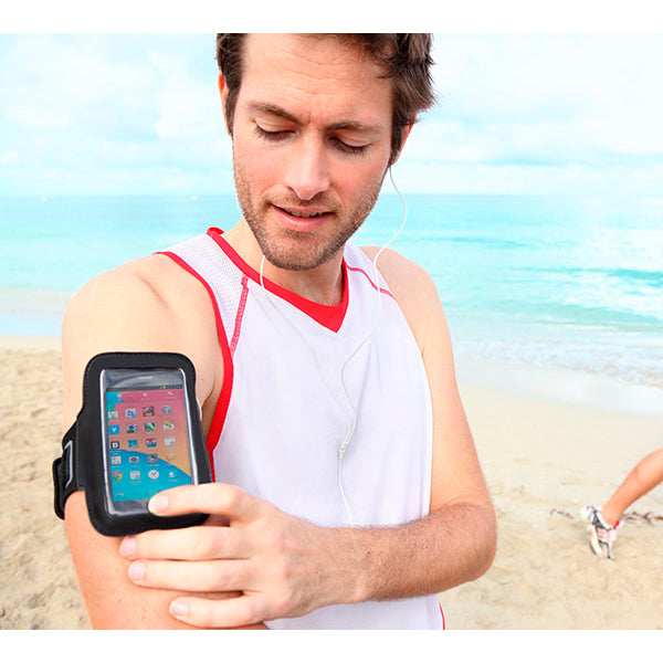 Man on a beach using a smartphone in an armband