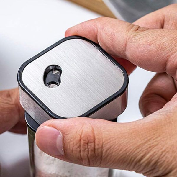 Close-up of a hand holding a small metallic device with a white face