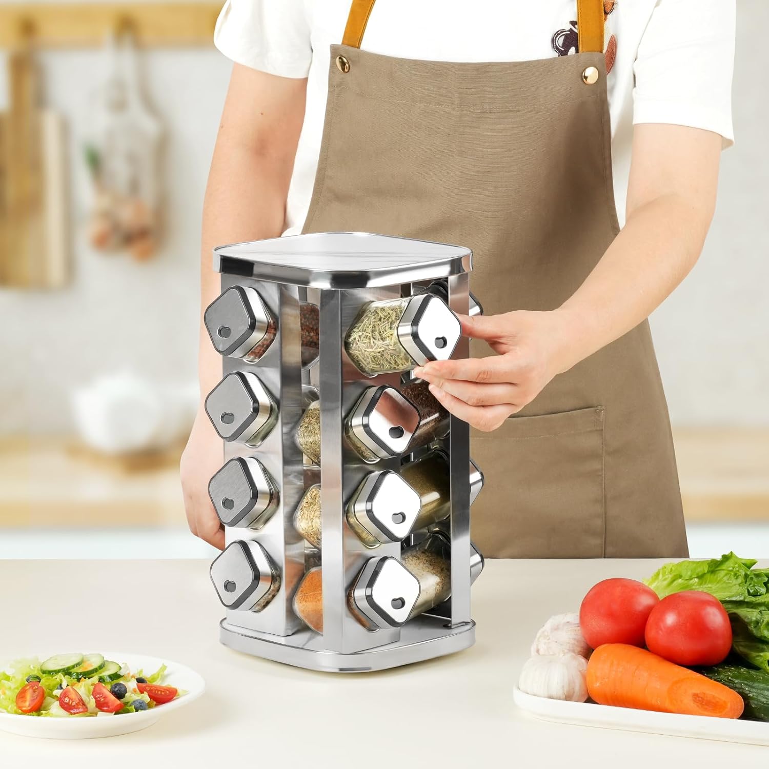 Person in a kitchen using a spice rack with various spices, surrounded by vegetables and a salad.