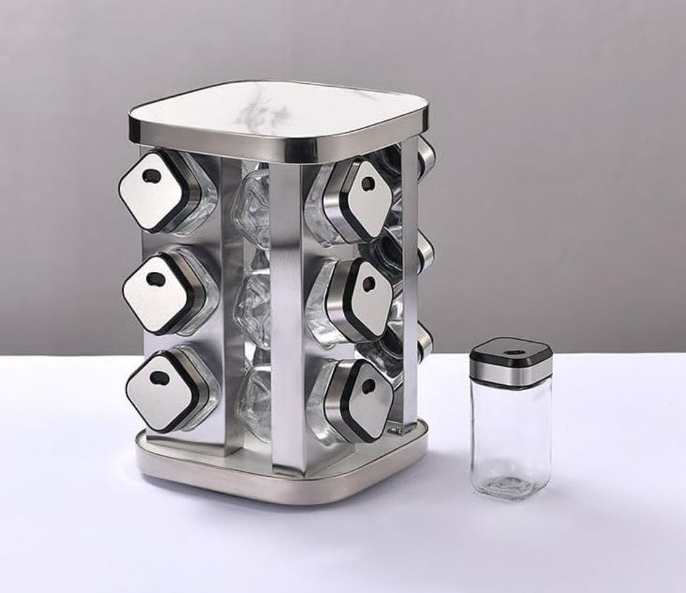 Stainless steel rotary spice rack with individual jars on a white surface.